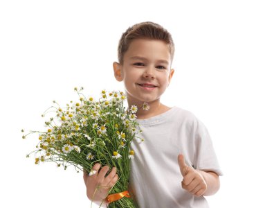 Gülümseyen küçük çocuk, elinde bir buket güzel papatya çiçeğiyle beyaz arka planda baş parmağını gösteriyor.