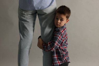 Küçük çocuk annesi olmadan gitmeye korkuyor ve gri arka planda ona sarılıyor. Ayrılık endişesi