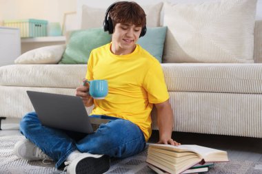 Bir bardak içki ve dizüstü bilgisayarla evde ders çalışan genç bir öğrenci.