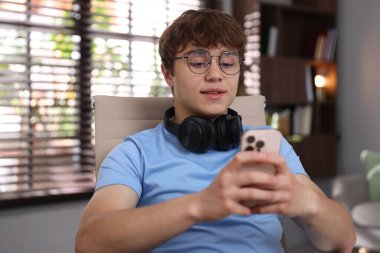 Evde ders çalışırken kulaklık takan genç bir öğrenci.