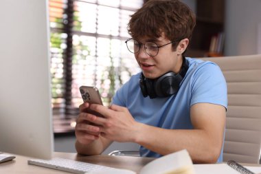 Evde ders çalışırken kulaklık takan genç bir öğrenci.