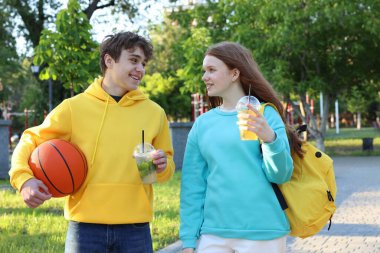 Parkta içki ve basketbol oynayan genç bir kız ve oğlan.