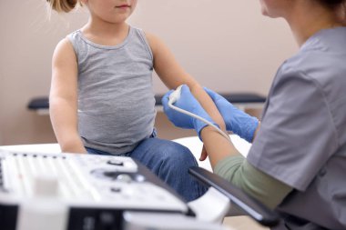 Sonograf, klinikte küçük bir kızın kolunun ultrason muayenesi yapıyor.