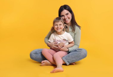 Mutlu anne ve tatlı kızı turuncu arka planda