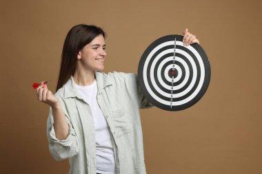 Hedef alınıyor. Bej arka planda ok ve dart tahtası olan gülümseyen kadın.