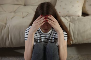 Depresyondaki genç kız evde yerde yatıyor.