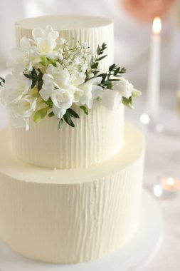 İçerideki masada çiçeklerle süslenmiş nefis düğün pastası, yakın plan.