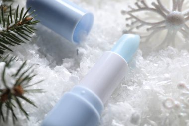 Nemlendirici dudak kremi, Noel dekorasyonu ve yapay kar üzerindeki köknar ağacı dalları, yakın plan. Kış bakımı