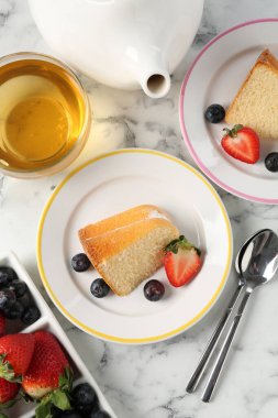 Böğürtlenli kek parçaları ve beyaz mermer masa üzerinde çay, düz yatıyordu