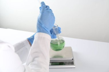 Beyaz masada numune ve ölçeklerle çalışan bilim adamı, yakın plan.