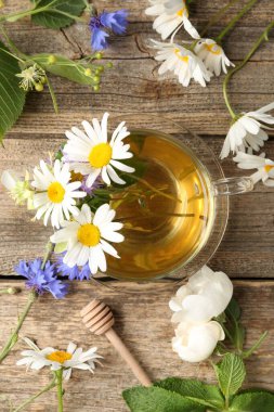 Cam bardakta Aromatik bitkisel çay, çiçekler ve ahşap masa, düz yatıyordu.