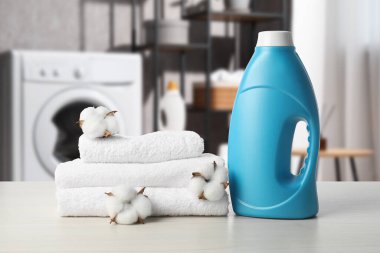 Çamaşır odasındaki masada yumuşatıcı, havlu ve pamuk çiçekleri var.