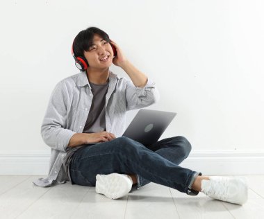 Kulaklık ve dizüstü bilgisayarı olan öğrenci içeride ders çalışıyor.