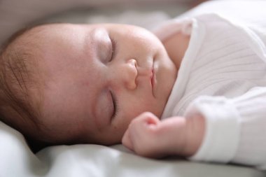Sevimli yeni doğmuş bebek yatakta uyuyor, yakın plan.