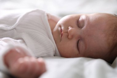 Sevimli yeni doğmuş bebek yatakta uyuyor, yakın plan.