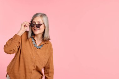 Pembe arka planda şık giyinmiş son sınıf öğrencisi kadın, mesaj için yer var.