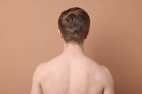 Man after scoliosis treatment on beige background, back view