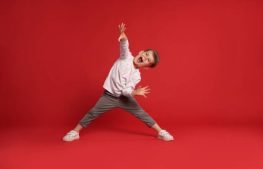 Kırmızı arka planda dans eden küçük mutlu çocuk, mesaj için boşluk