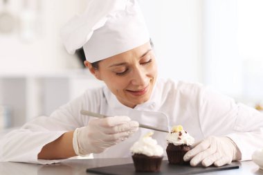 Cımbızlı şekerlemeci mutfakta kek süslüyor.