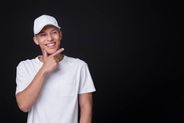 Siyah arka planda şık beyaz beysbol şapkası giyen genç adam, mesaj için yer var.