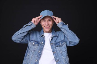 Siyah arka planda şık kot şapkalı genç adam.