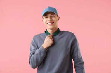 Pembe arka planda şık bir beyzbol şapkası takan genç adam.