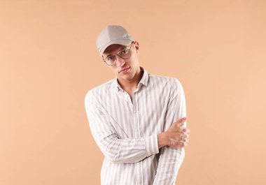 Beyzbol şapkalı genç adam bej arka planda.