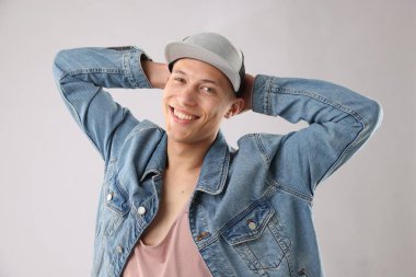 Açık gri arka planda şık bir beyzbol şapkası takan genç adam.