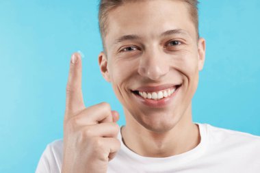 Açık mavi arkaplanda kontak lensli adam, yakın plan