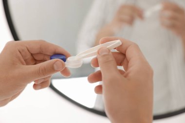 Evdeki aynanın yakınındaki kutudan lensleri alan adam, yakın plan.