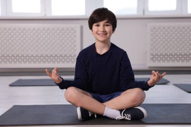 Kapalı alanda yoga yapan mutlu çocuk.