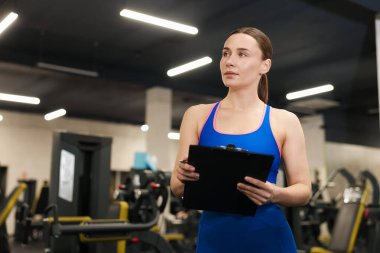 Spor salonunda panosu olan profesyonel bir antrenör. Metin için boşluk