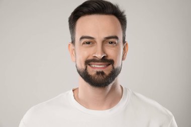 Gri arka planda gülümseyen adamın portresi, yakın plan.