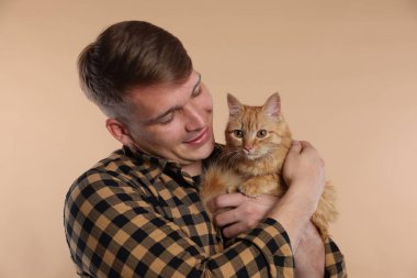 Bej arka planda sevimli kızıl kedisi olan adam.