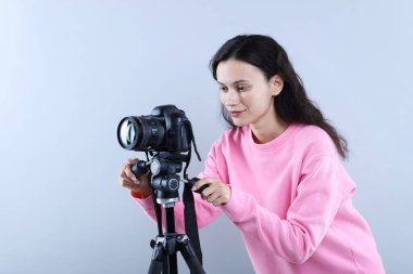 Açık gri arkaplanda profesyonel video kamerası olan kadın