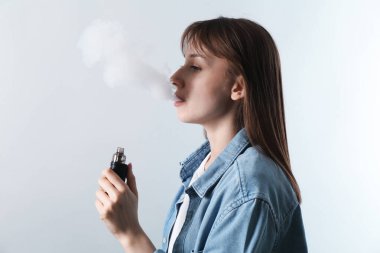Açık gri arkaplanda elektronik sigara içen kadın