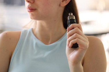 Dışarıda elektronik sigara içen genç bir kadın, yakın plan.