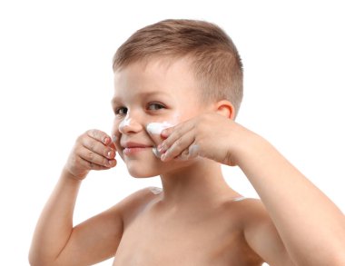 Küçük çocuk beyaz arka planda cildine güneş kremi sürüyor.