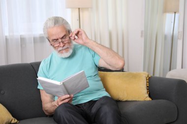 Evdeki kanepede kitap okuma sorunu olan son sınıf öğrencisi.