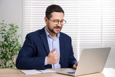 Gülümseyen çevrimiçi hoparlör masadaki dizüstü bilgisayarla internetten yayın yapıyor.