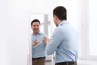 Yakışıklı adam aynada kendine bakıyor.