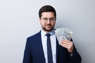 Gri arka planda dolar banknotları olan açgözlü bankacı.