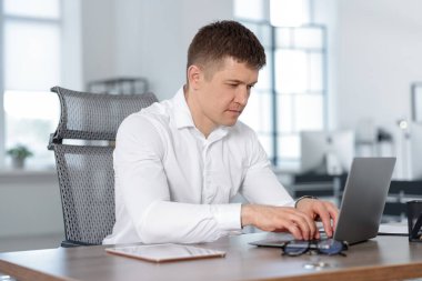 Ofiste masada dizüstü bilgisayarda çalışan adam