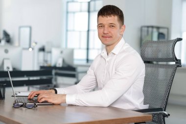 Ofiste masada dizüstü bilgisayarda çalışan adam