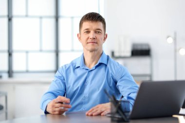 Ofiste masa başında çalışan yakışıklı adam.