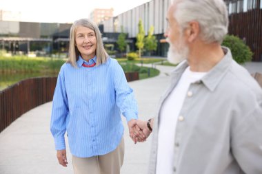 Şehir caddesinde birlikte yürüyen sevimli yaşlı çift.