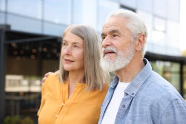 Güzel yaşlı çift bina yakınlarında birlikte yürüyorlar.