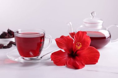 Lezzetli amber çayı, kuru roselle sepals ve gri arka planda beyaz mermer masada güzel bir çiçek.