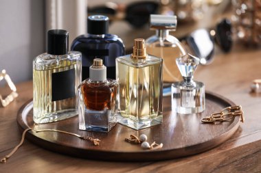 Farklı parfüm şişeleri ve aksesuarlar ahşap masada, yakın plan.