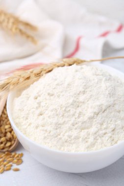 Buğday unu kasede, tahıllar ve çiviler beyaz masada, yakın plan.